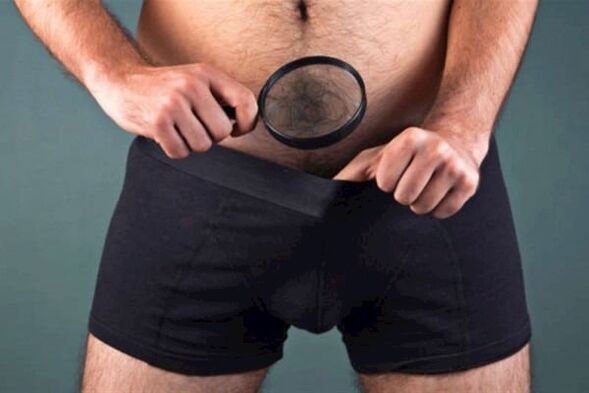 虫眼鏡を持った男性が自分のペニスを調べ、それを太くしたいと考えています